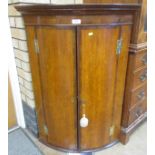 A late Georgian oak bow front Corner Cupboard with pair of cross-banded doors