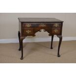 An 18th Century oak Lowboy fitted three drawers surrounding a shaped frieze on cabriole supports,