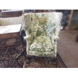 A George II style mahogany wingback Armchair, upholstered green floral print, carved shell, claw and