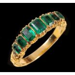 An Emerald seven stone Ring close-set graduated step-cut stones in carved mount, ring size L