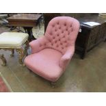 A Victorian Occasional Chair with pink button upholstery on turned front legs and casters