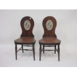 A pair of 19th Century mahogany Hall Chairs, balloon backs painted with oval crests, shaped seats