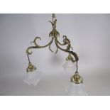 An antique brass three branch Electrolier of leafage form with opaque glass floral shades, 1ft 6in