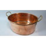 An Oval Copper Cooking Pot with Twin Brass Handles, 37cm Wide