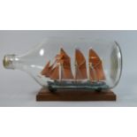 A Continental Folk Art Ship in a Bottle, 35cm Long on Plinth Stand