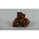 A Carved Wooden Netsuke in the form of a Pig with a Peach