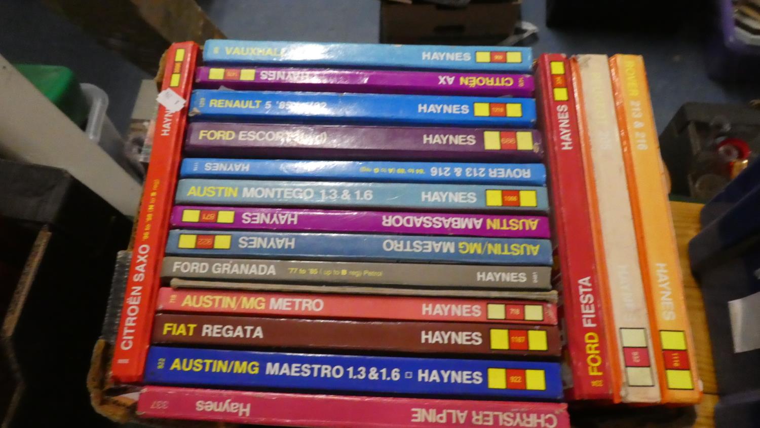 A Box Containing Eighteen Haynes Workshop Manuals and Six Giles Cartoon Annuals