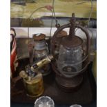 A Tray Containing Four Hurricane Lamps and a Blow Torch