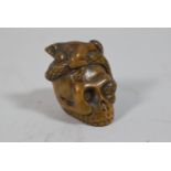 A Carved Wooden Netsuke in the Form of Skull Adorned with Snake Engulfing Toad, 3cm high