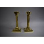 A Pair of Polished Brass Corinthian Column Candlestick on Stepped Square Bases, 23cms High