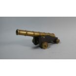 A Bronze Desk Top Model of a Signal Cannon on Wooden Carriage with Bronze Wheels. 26cms Long.