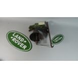 A Reproduction Cast Metal Wall Hanging Landrover Bell Together with Two Oval Land Rover Plaques (