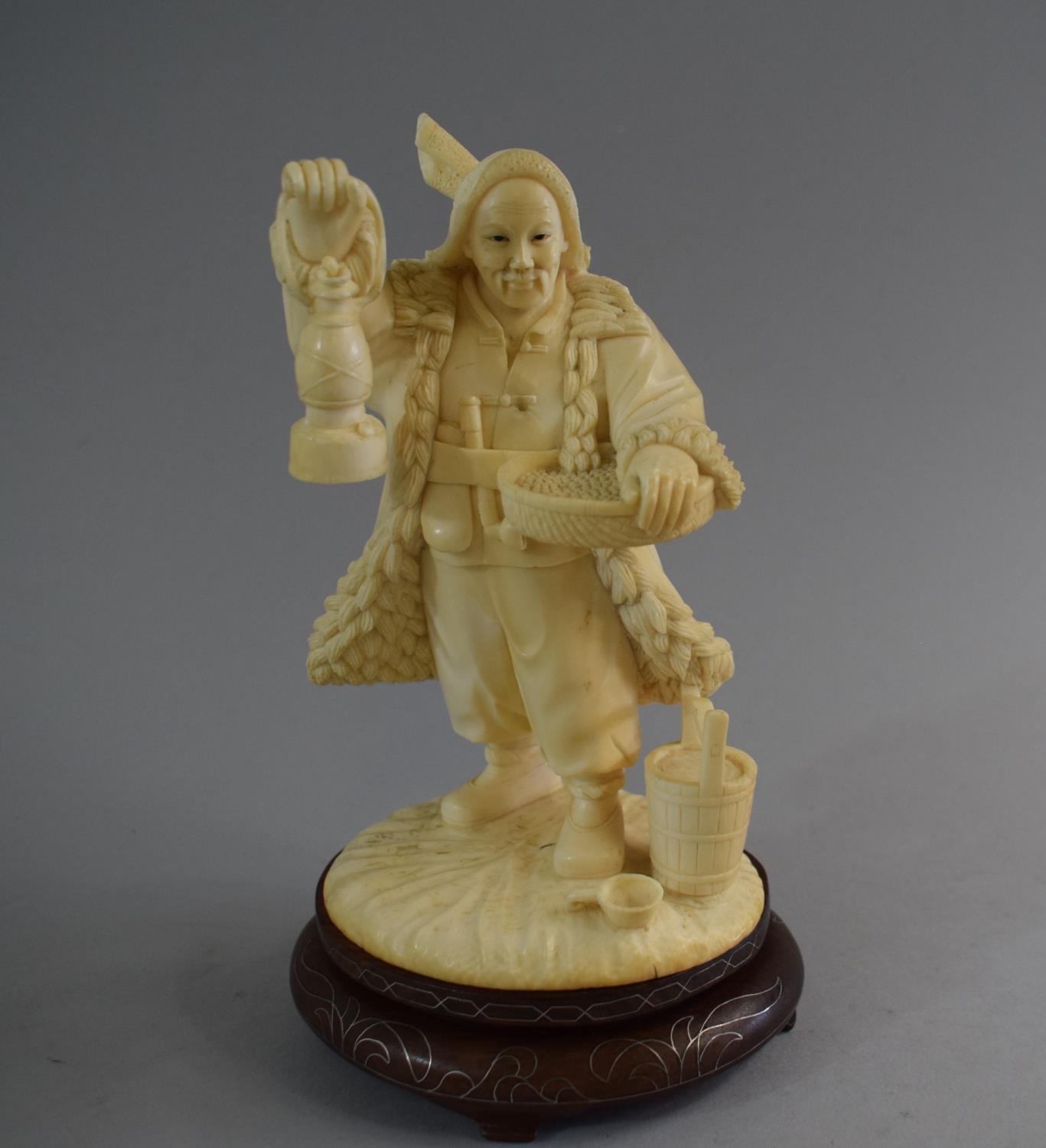 A Carved Chinese Ivory Figure in the Form of Standing Farmer Holding Lantern and Basket. Set on
