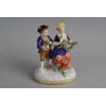 A Continental Figural Group Depicting Boy playing Pipe and Girl with Floral Swag. 17cms High