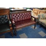 A Wooden Framed Buttoned Red Upholstered Two Seater Pub Settle with Scrolled Arm Supports, 101cm