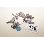 A SILVER CHARM BRACELET WITH 23 CHARMS, SOME WITH ENAMEL DETAILING, 49G