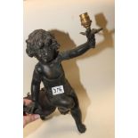A CAST BRONZE CHERUB SITTING ON A WOODEN SHELF WIRED TO BE USED AS AN ELECTRIC LIGHT