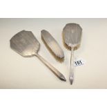 A THREE PIECE SILVER TOPPED DRESSING TABLE SET COMPRISING TWO BRUSHES AND A HAND MIRROR,