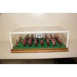 A QUANTITY OF TOY SOLDIERS MOUNTED ON A BASE TO FORM A MUSICAL BAND IN A GLASS CASE