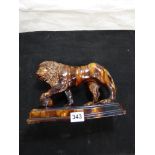 TREACLE GLAZED ROCKINGHAM STYLE CERAMIC FIGURE OF A LION WITH ITS PAW ON A BALL