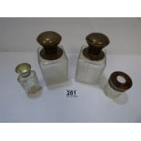 TWO WHITE METAL TOPPED GLASS BOTTLES, 14CM HIGH AND TWO OTHER WHITE METAL TOPPED TOILETRIES BOTTLES