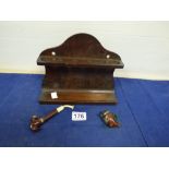 A WOODEN PIPE RACK WITH HOLES FOR SIX PIPES TOGETHER WITH A VINTAGE PIPE EMBOSSED