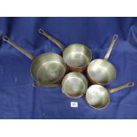 A SET OF FIVE COPPER AND BRASS GRADUATED SAUCEPANS, LARGEST 40CM IN LENGTH