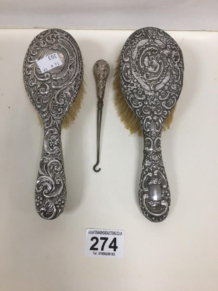 TWO HALLMARKED SILVER HAIR BRUSHES WITH EMBOSSED DECORATION AND A SIMILAR BUTTON HOOK