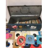 A LARGE METAL LIDDED TIN CONTAINING A LARGE COLLECTION OF VINYL SINGLE RECORDS