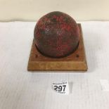 A C.1800 ANTIQUE IRON CANNONBALL RAISED UPON WOODEN STAND, THE BALL ITSELF MEASURES APPROX 9CM