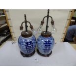A PAIR OF CHINESE BLUE AND WHITE CERAMIC TABLE LAMPS, BOTH RAISED UPON WOODEN STANDS (ONE AF),