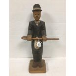 A CARVED WOODEN MODEL DEPICTING A GENTLEMAN IN A SUIT WEARING A HAT AND HOLDING A WALKING STICK,