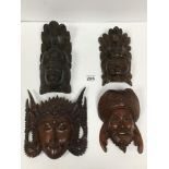 FOUR VINTAGE ORIENTAL WOODEN WALL CARVINGS OF FACE MASKS SOME WITH GLASS EYES, LARGEST 15CM