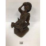 A HEAVILY CARVED HARDWOOD FIGURE OF A COWBOY DRINKING A DRINK IN ONE HAND A CIGARETTE IN THE