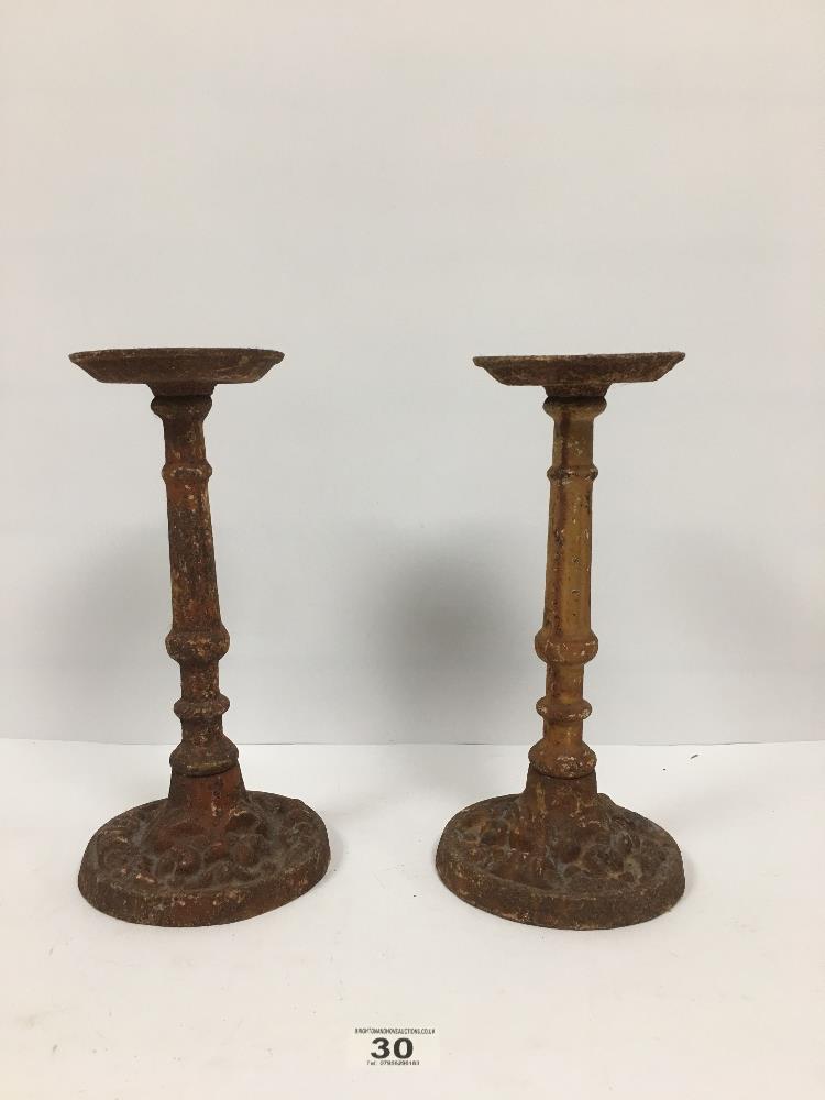 A PAIR OF SMALL HEAVY CAST IRON SPIT CANDLESTICKS, 29CM HIGH