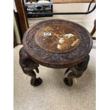 A SMALL WOODEN CARVED INDIAN TABLE WITH INLAID DETAILING TO THE TOP DEPICTING ELEPHANTS AMONGST PALM