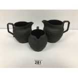 A GRADUATED SET OF THREE LATE 19TH CENTURY WEDGWOOD BLACK BASALT MILK JUGS WITH RELIEF DECORATION,