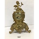 A HEAVY BRASS MANTLE CLOCK, THE TOP ADORNED WITH A CHERUB FINIAL, QUARTZ MOVEMENT, 38CM HIGH