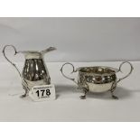 A SILVER CREAM JUG WITH MATCHING SUGAR BOWL, BOTH RAISED UPON CLAW FEET, HALLMARKED BIRMINGHAM