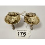 A PAIR OF VICTORIAN SILVER SHELL SHAPED SALTS, EACH RAISED UPON THREE DOLPHIN LEGS, HALLMARKED