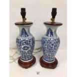 A PAIR OF ORIENTAL BLUE AND WHITE CERAMIC TABLE LAMPS, RAISED UPON WOODEN BASES WITH WOODEN TOPS,