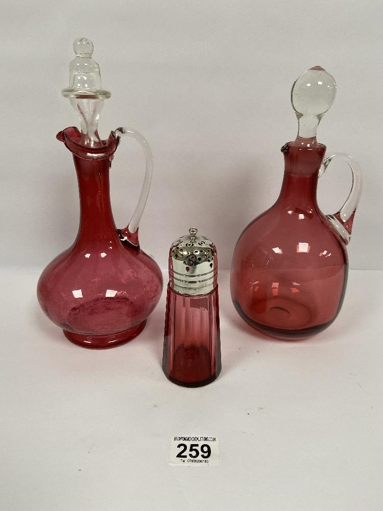 TWO VICTORIAN CRANBERRY GLASS DECANTERS, LARGEST 30CM HIGH, TOGETHER WITH A SIMILAR SUGAR SIFTER