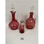 TWO VICTORIAN CRANBERRY GLASS DECANTERS, LARGEST 30CM HIGH, TOGETHER WITH A SIMILAR SUGAR SIFTER