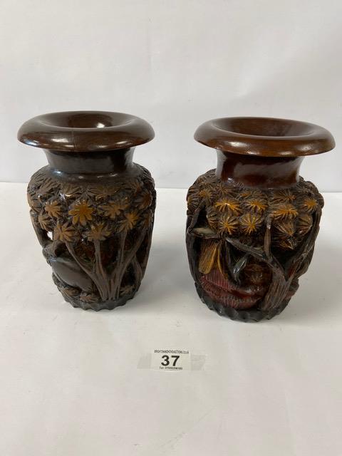 A PAIR OF CARVED WOODEN VASES SHOWING ELEPHANTS AMONGST TREES AND HOUSES, 20CM HIGH