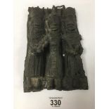 AN USUAL BRONZE WALL PLAQUE IN THE BENIN STYLE, DEPICTING THREE TRIBES PEOPLE HOLDING WEAPONS,