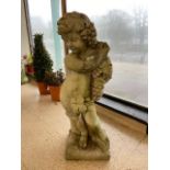 A LARGE CONCRETE STATUE OF A CHILD HOLDING GRAPES SAT ON A TREE STUMP 91 CMS