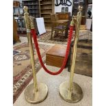 A PAIR OF GILT STANCHIONS ATTACHED WITH RED ROPE