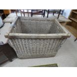 A LARGE WICKER INDUSTRIAL LAUNDRY BASKET ON WHEELS.