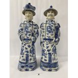 A PAIR OF CHINESE BLUE AND WHITE CERAMIC FIGURES OF ELDERS, BOTH WEARING HATS, CHARACTER MARKS TO