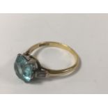 A LADIES 18CT GOLD AND PLATINUM RING WITH LARGE BLUE TOPAZ FLANKED BY TWO SINGLE BAGUETTE